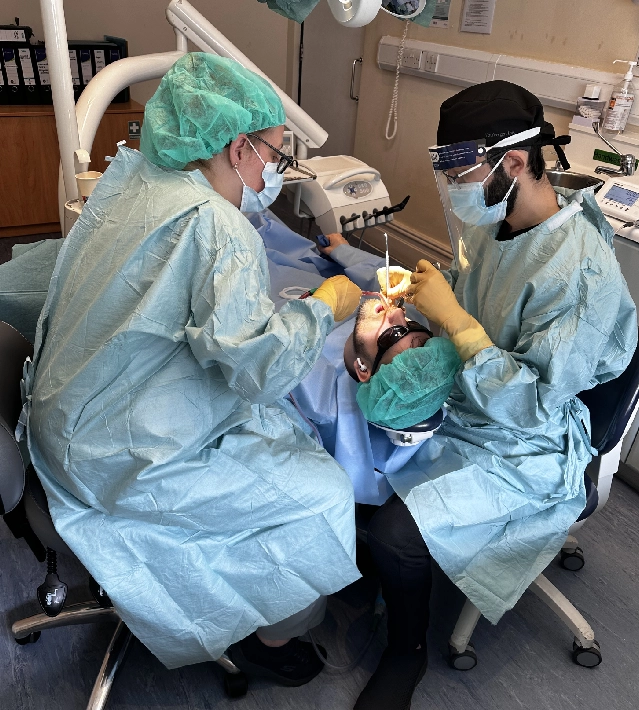 Two people in scrubs and masks are operating a patient.