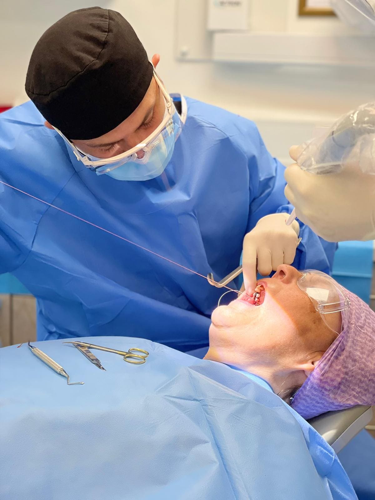 A dentist is performing an operation on someone 's face.